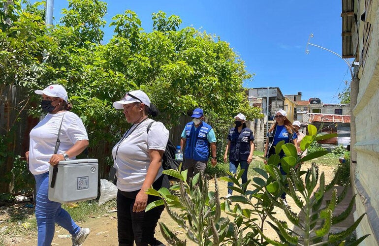 Health workers carrying vaccines in coolers to remote areas