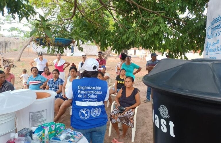 personal de OPS entregando filtros y tanques  de agua a comunidad