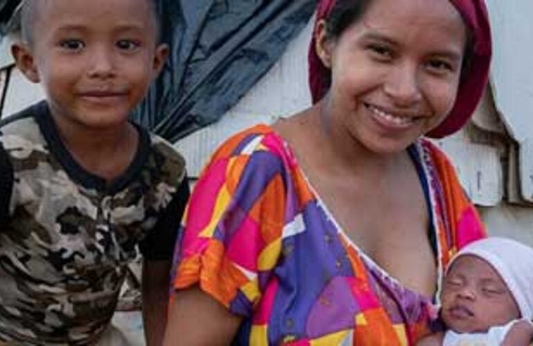 Mujer con niño y bebé, sonriendo a la cámara