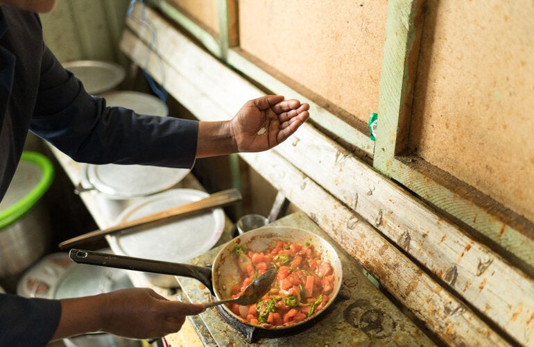 Pessoa adicionando sal à comida enquanto ela cozinha