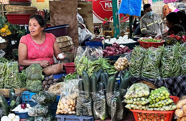 mujer vendiendo verduras en mercado tradicional en Guatemala