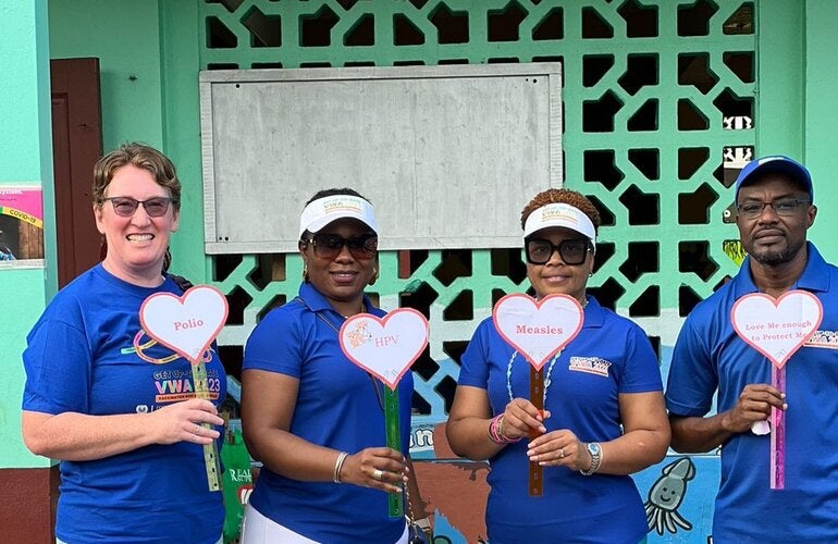 Group standing with vaccination placards