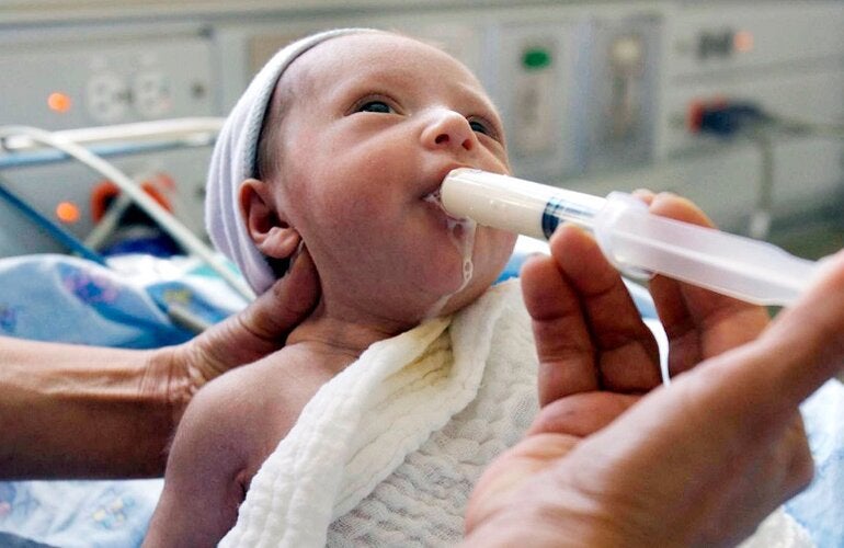 Bebé siendo alimentado de leche humana a través de una jeringa