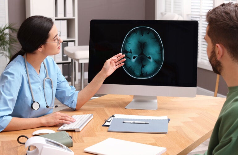 A female health worker shows the image of the brain to a male patient