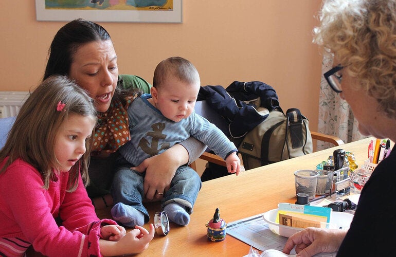 A doctor explaining vaccination procedures to a mother with her two young children.