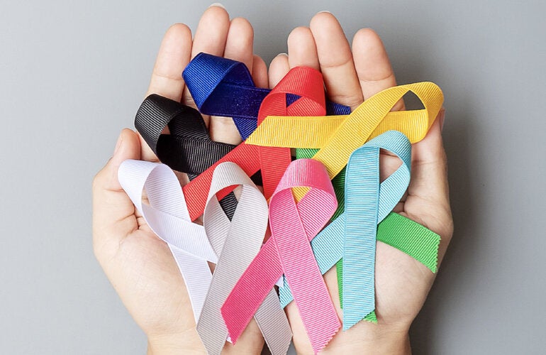 Hands with ribbon of the different colors representing various cancer types