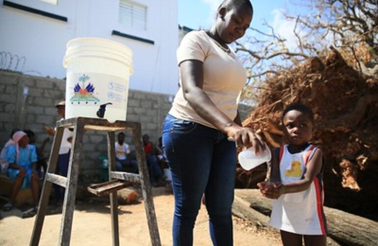 Girl washing hands of a child to prevent him from cholera