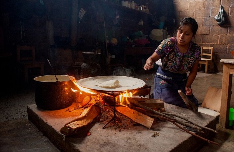Mujer maya cocinando al fuego