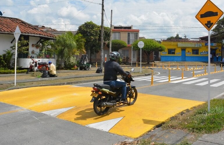 Motociclista en la calle pasando un reductor de velocidad