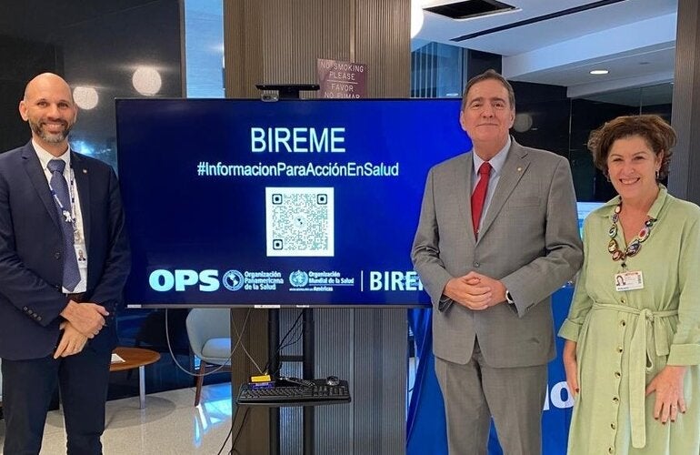 A foto mostra o Dr. Barbosa, Diretor da OPAS, com João Paulo Souza, Diretor da BIREME, e Verônica Abdala, Gerente da BIREME. Eles estão em frente ao estande da BIREME no CD61.