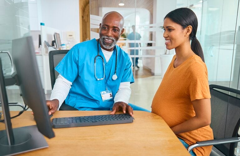 Male doctor and pregnant patient review electronic medical records