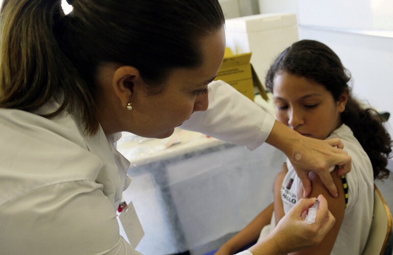 vacunando un niña con uniformer escolar