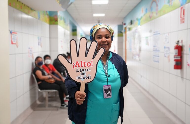 personal de salud sostiene una pancarta alusiva a la higiene de manos