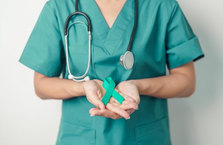 A female doctor with a teal shirt holds a teal ribbong in her hands. The human figure appears from the shoulders to the waist, as the hands are the important element in the picture