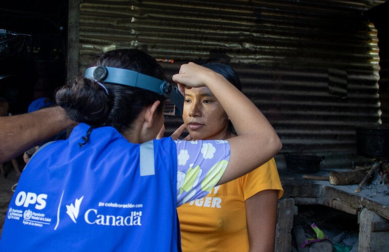 una mujer de OPS realizando atención primaria sobre una mujer de la comunidad