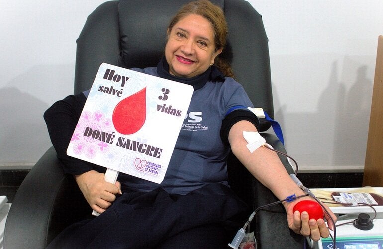 Donante de sangre posa con un rótulo de las vidas salvadas a raíz de la donación