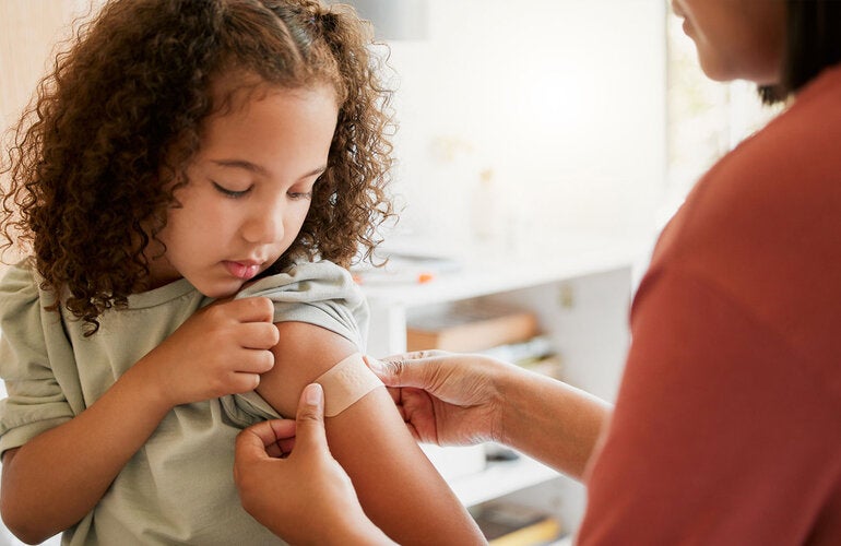 Girl gets a band aid after being vaccinated