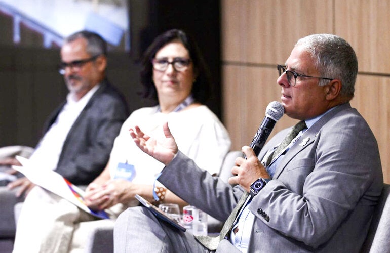 Dr. Cristian Morales, de cabelos brancos, discursa com microfone na mão