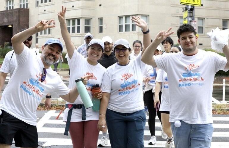 Happy people with a t-shirt showcasing a walk for health are walking and waving their hands