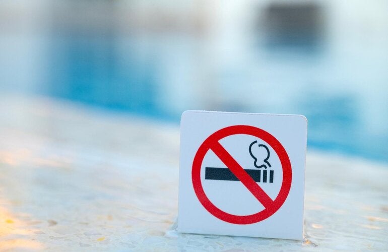 Signo de "no fumar". Está prohibido fumar en lugares públicos. Señal de prohibición cerca de agua azul en la piscina