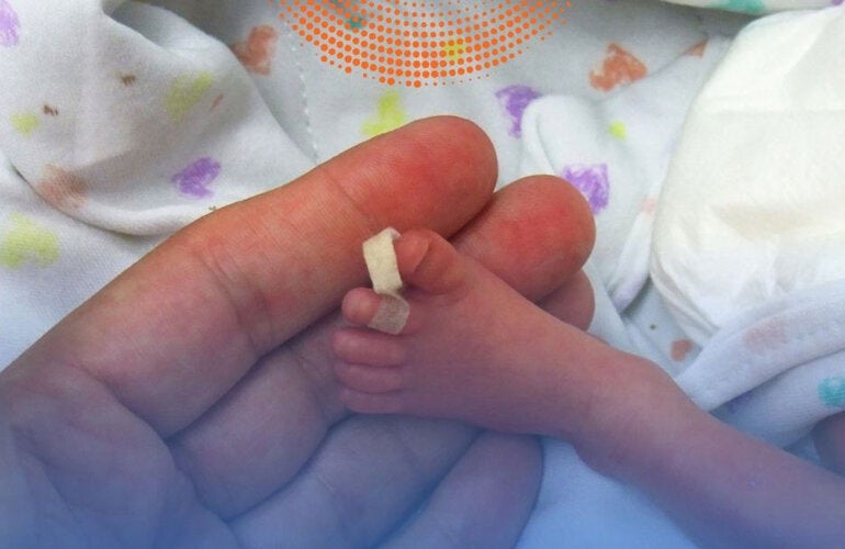 Foot of premature baby on a mother's hand