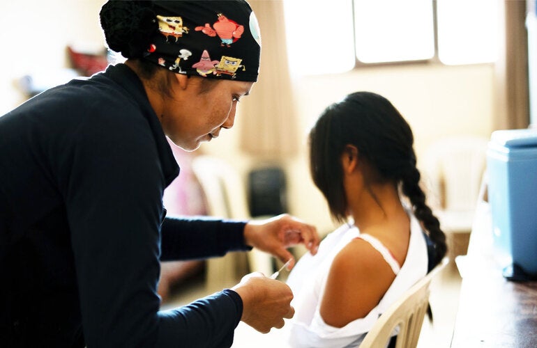 Health care worker applying a vaccine to a girl