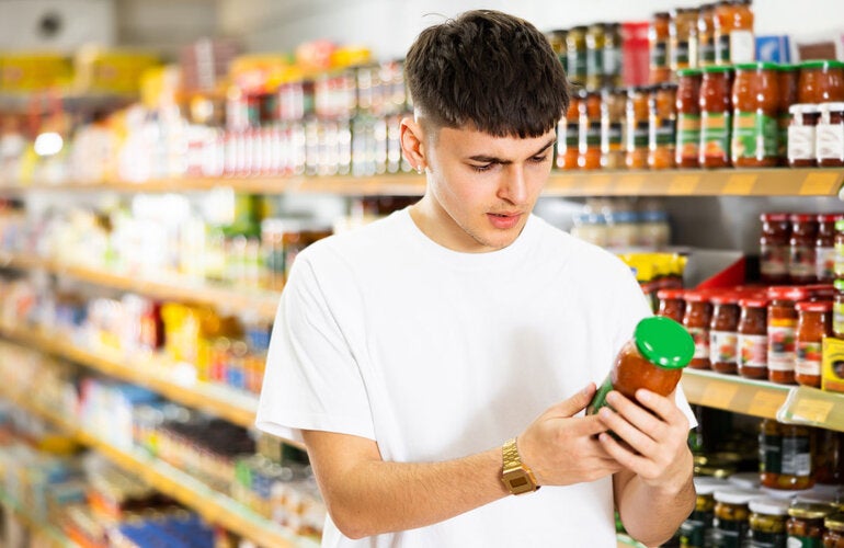 Un hombre joven leyendo la etiqueta frontal del producto (salsa)