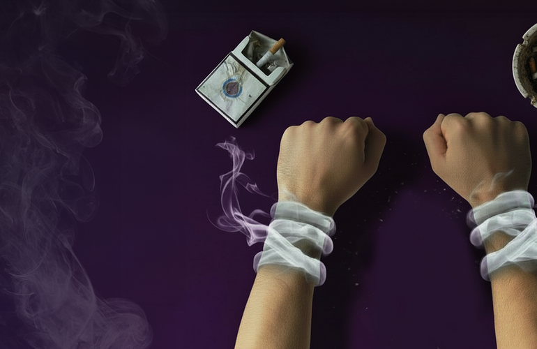 Mano esposada por el humo proveniente de un paquete de cigarrillos y un cenicero sucio.