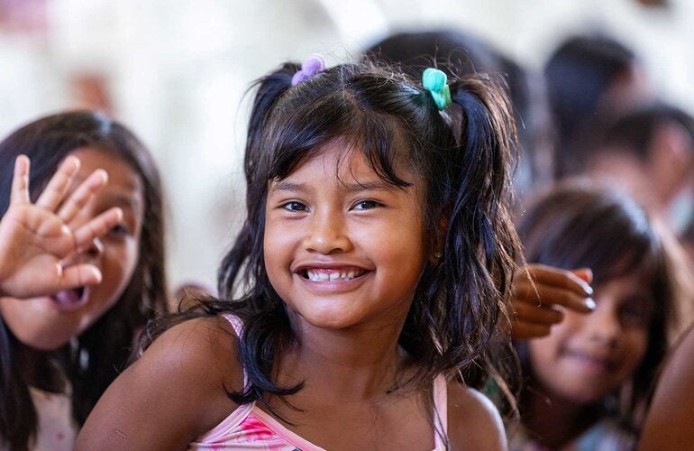 Menina sorrindo e acenando para a câmera