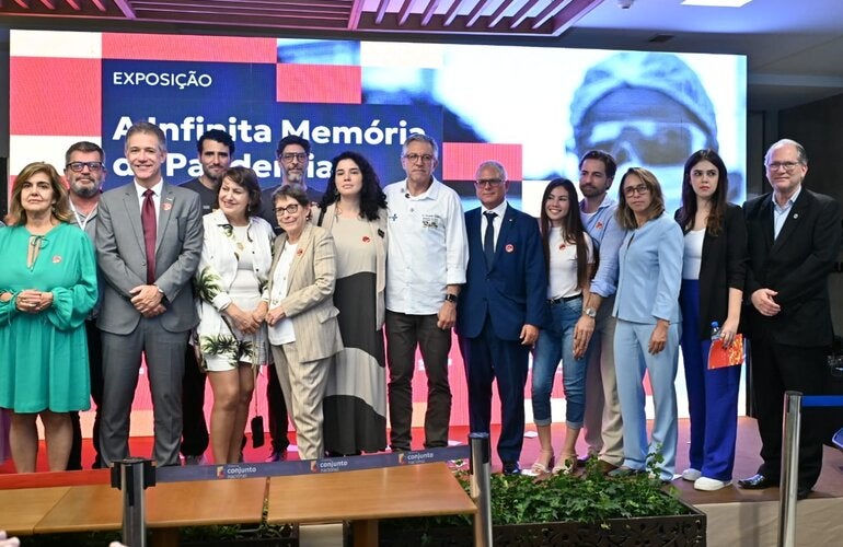 Authorities, researchers, and representatives of partner institutions and civil society pose for a photograph during the opening ceremony of the traveling exhibition “The Infinite Memory of the Pandemic”, held in Brasília, Federal District, Brazil. Present are Brazil’s Minister of Health, Alexandre Padilha, and PAHO Representative in Brazil, Cristian Morales, alongside members of the Digital Memorial of the COVID-19 Pandemic team. In the background, a digital screen displays the exhibition’s visual identity