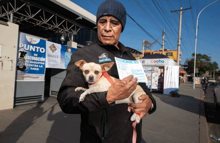 hombre con perro en brazos y la cartilla de vacunación