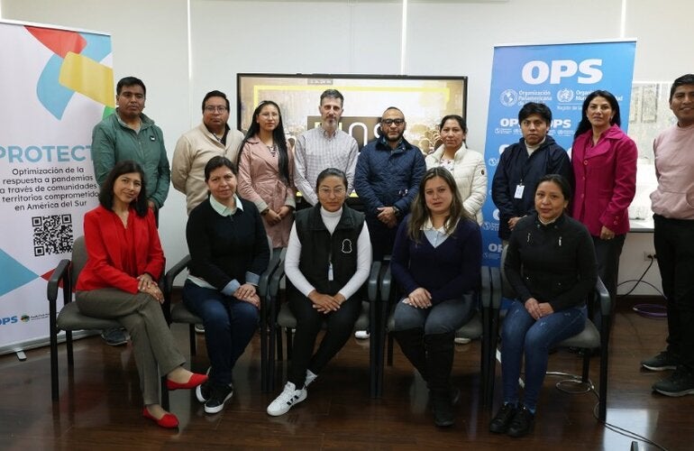 participantes de taller posan para foto junto a banners del evento