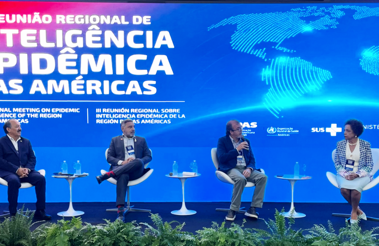 Panelistas sentados con fondo alusivo al evento, mostrando mapa mundi y título del evento