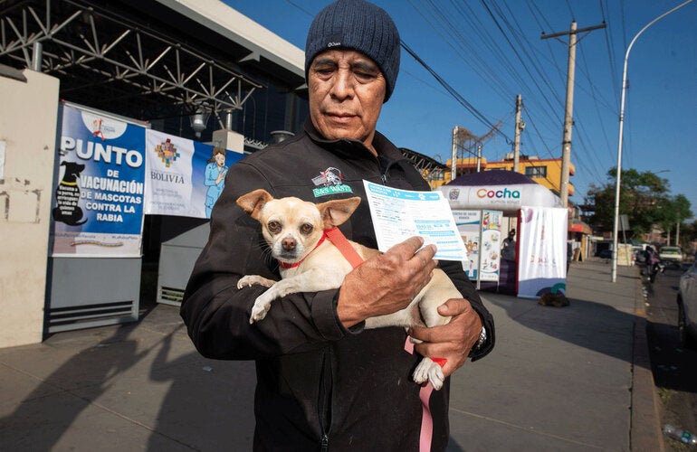hombre con perro en brazos y la cartilla de vacunación