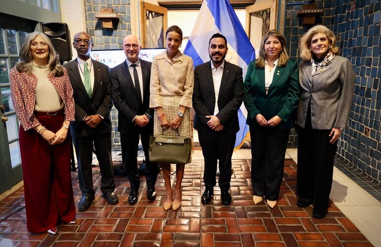 siete personas paradas en frente de la bandera de El Salvador