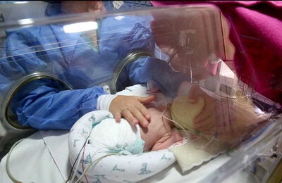 Madre mira a su hija en la incubadora
