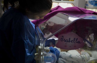 Madre acariciando su bebé en la Unidad de Cuidados Intensivos Neonatales