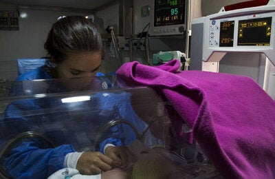 Madre acariciando su bebé en la Unidad de Cuidados Intensivos Neonatales