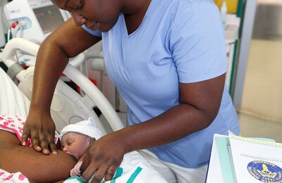 Nurse aids new mom with breastfeeding