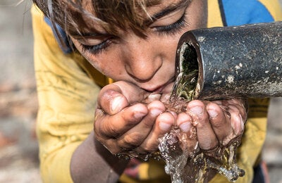 Niño tomando agua contaminada