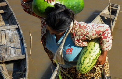 Woman with watermelons and fish in hand