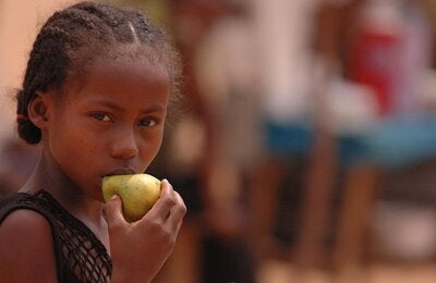 Photo of a young girl with braided hair eating a pear
