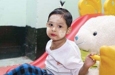 Photo of a young girl with her face painted and seated next to a giant stuffed rabitt