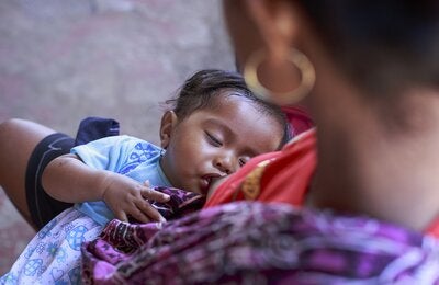 Close up of a baby on her mother arms being breastfed