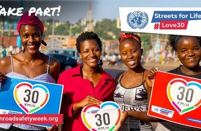 Picture of four Black women smiling and holding posters with 30 km/h inside a heart