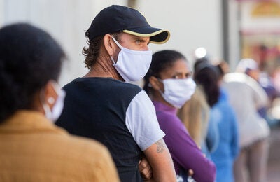 Las personas esperan para entrar a un estblecimiento usando mascarillas.
