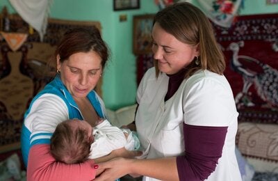 A community nurse examines a newborn baby