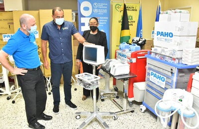 Dr. the Hon. Christopher Tufton, Jamaica's Minister of Health and Wellness (centre) discusses a patient monitor that will be used to assess the needs of a patient’s changing condition. Looking on are (L-R) Mr. Ian Stein, PAHO/WHO Representative to Jamaica, Bermuda and the Cayman Islands and Dr. Marion Bullock DuCasse, Advisor, Health Emergencies