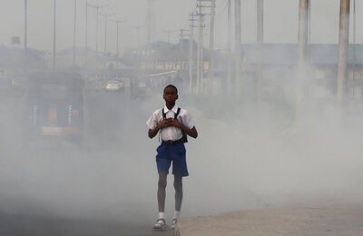 Niño caminando en ciudad con aire contaminado.