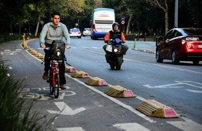 Cyclist circulating on a separate cyclist lane, behind him, a motorcyclist and two vehicles